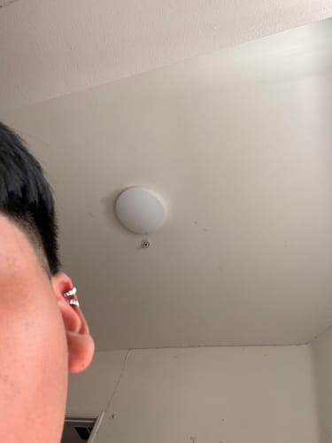 Close-up of a reviewer's ear showing two shiny silver-colored cartilage hoop earrings.