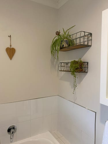 Reviewer's Aurelie wire wall baskets mounted in a bathroom corner, holding small potted plants above a tiled wall.