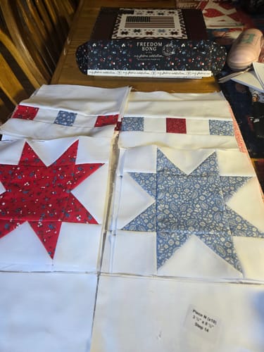 Reviewer showing their progress on the Freedom Song Quilt Kit, with assembled red and blue star blocks laid out.