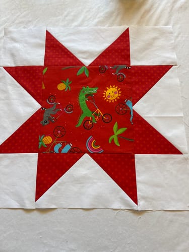 Customer's cute star quilt block from the Cut Flowers pattern, featuring red points and a whimsical animal fabric center.