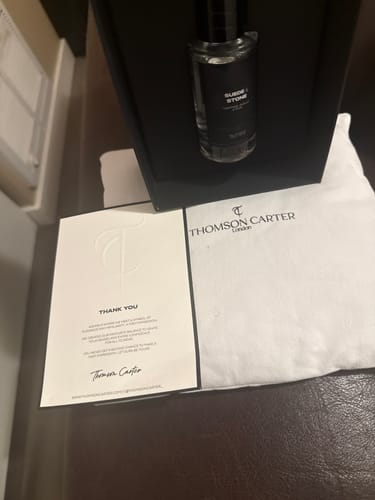 Customer's Suede & Stone Eau de Parfum bottle inside a black presentation box with a branded thank you card.