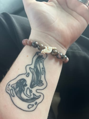 Reviewer wearing the beaded Dash Bracelet with a white red panda charm on their wrist.