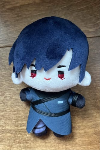 Customer's Alien Stage plush doll with dark hair and blue outfit, resting on a wooden surface.