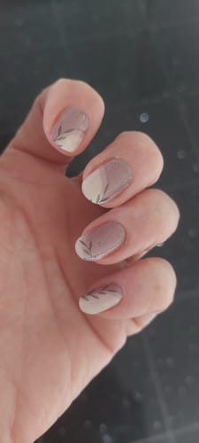 Kundenhand zeigt die aufgetragenen UV Gel Nail Wraps Stone Minimalist mit zartem Blattmuster auf Nude und Blush Tönen.