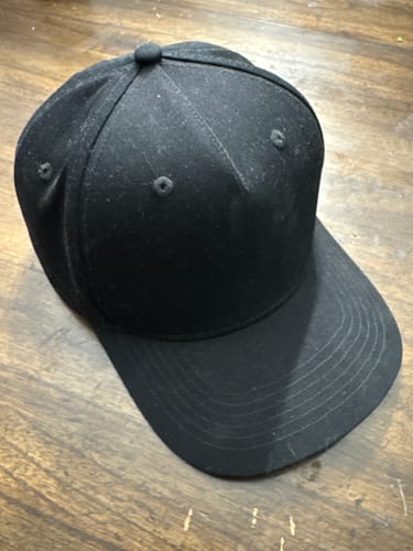 Customer's black structured A-Frame hat resting on a wooden surface