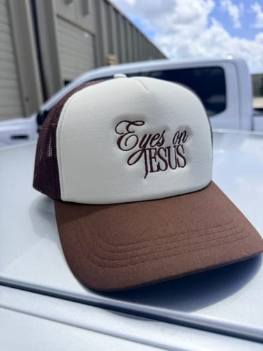 Reviewer's custom foam trucker hat with brown mesh back and white front featuring Eyes on Jesus embroidery.