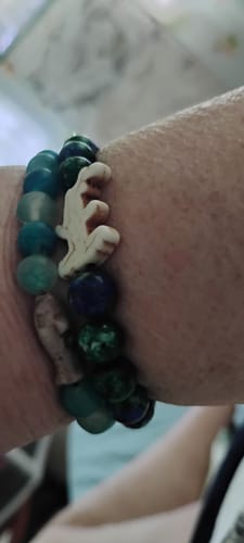 Customer's wrist wearing two stacked colorful bead bracelets, one featuring a decorative animal charm.