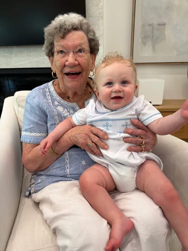 Customer's baby in the white Blue Cross Smocked Boy Bubble sitting on a person's lap.