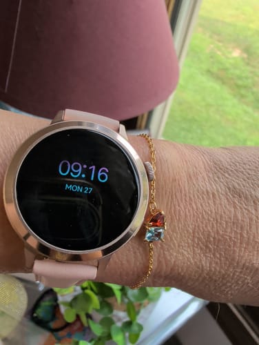 Reviewer's Forever Duo Birthstone Bracelet with colorful teardrop gems on a gold chain, worn with a smartwatch.