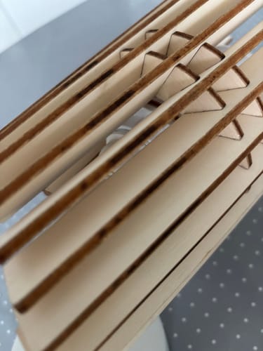 Reviewer's Perle applique showing detail of charred, dark edges on the layered wooden components.