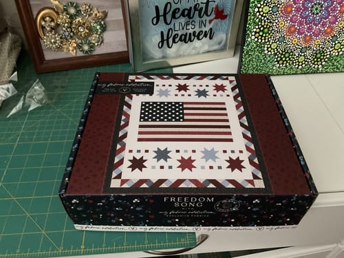 Customer's Freedom Song quilt kit box featuring an American flag design on a cutting mat.