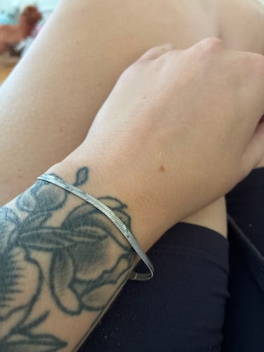 Customer's silver waterproof bracelet from the 7 for $85 bundle worn on a tattooed wrist.