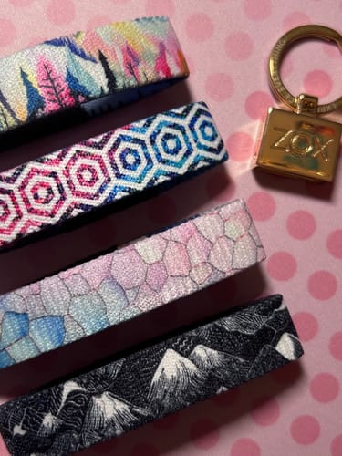 Customer's Encouragement Pack of four colorful bracelets with unique patterns and a gold ZOXLOX keychain on pink paper.