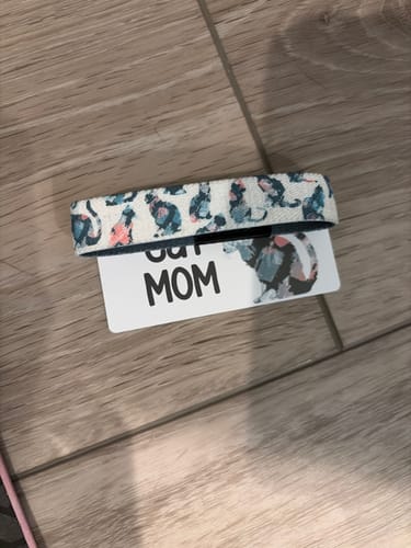 Customer's Cat Mom bracelet with a cat-patterned fabric band resting on its Cat Mom branded product card.