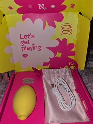 Customer's yellow Lem clitoral massager and white charging cable inside the open product box.