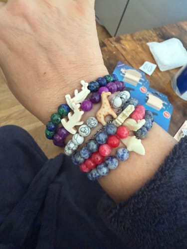 Reviewer's wrist wearing multiple Shark Week Bracelets featuring beaded bands with shark and giraffe charms.