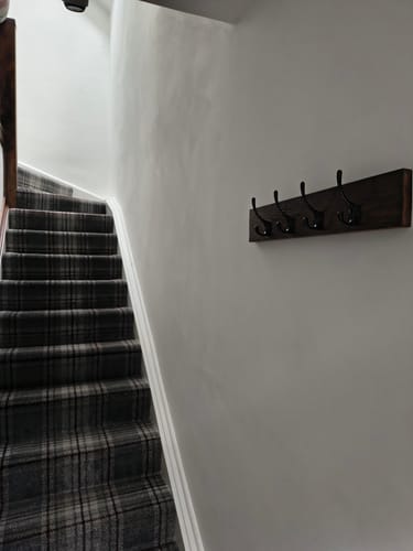 Customer's solid oak coat hanger with five hooks mounted on a hallway wall next to a staircase.
