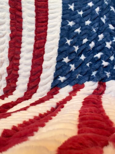 Close-up of a customer's plush Hugs Flag Blanket, showing the soft texture of the American flag pattern.