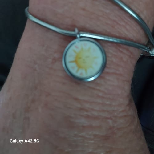 Customer's Sun Charm Bracelet, a close-up shot of the round charm featuring a sun design on a wrist.