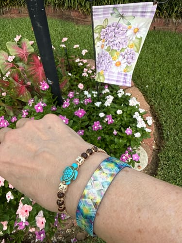 Customer's Here & Now bracelet worn on wrist outdoors, with a turtle charm bracelet next to it.