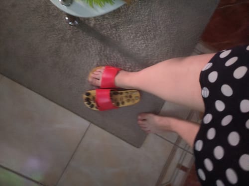 Customer's foot wearing an Akupresszúrás papucs with a red strap and textured brown footbed.