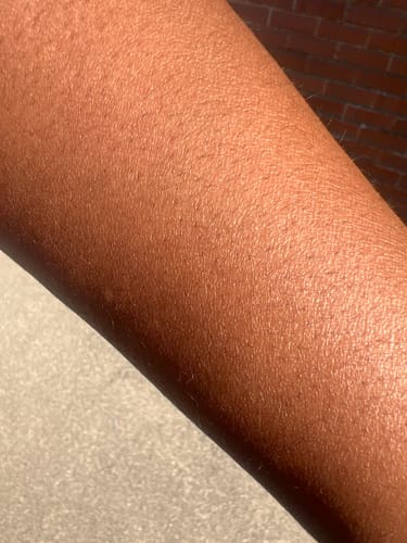 Customer's arm showing smooth, glowing skin one day after applying Sweet Skin Body Oil Bundle.