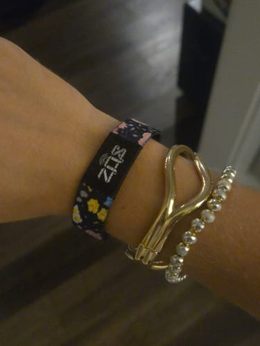Customer's floral In a Field of Roses bracelet worn on a wrist alongside two other bracelets.