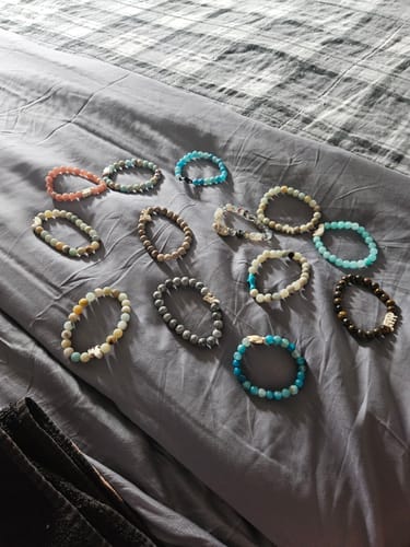 Customer's collection of various colorful beaded Fahlo Monthly Club bracelets displayed on a gray blanket.