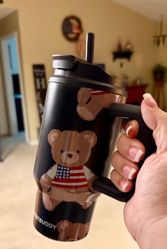 Reviewer's hand holding a black Thicc Buddy mug decorated with teddy bear patterns and an American flag design.