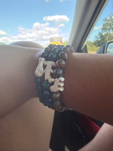 Customer's Shark Week Bracelet with hammerhead charm and dark beads, worn on a wrist in a car.