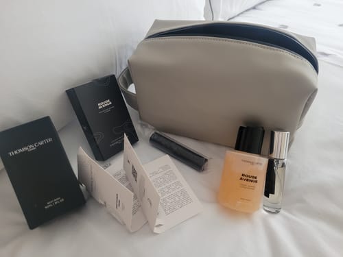 Customer's Rouge Avenue body wash bottles, black boxes, and instruction booklets packed in a beige travel pouch.