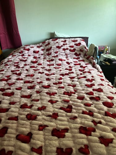 Customer's plush Hugs Heart Red Blanket with red hearts on a pink background, spread over a bed