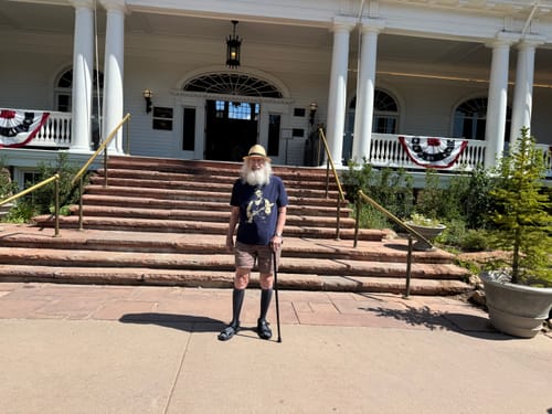 Customer's Rushmore Tour 250 T-Shirt on a person standing on the stone stairs at the historic Stanley Hotel.