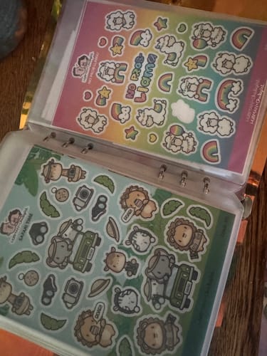 Customer's Sticker Subscription sheets featuring llama and safari animal designs, organized in a binder.
