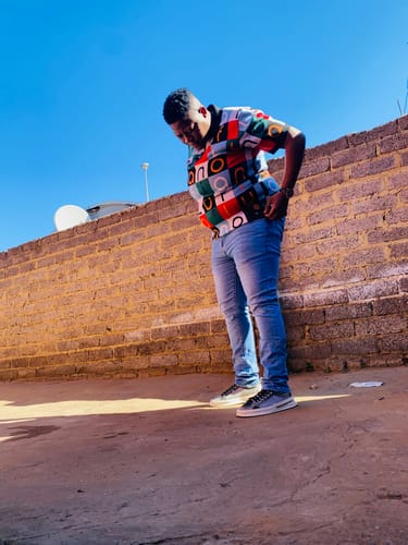 Customer's LFN007 knit top with a vibrant, geometric pattern worn outdoors against a brick wall.