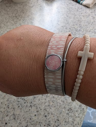 Customer's Sun Charm Bracelet, a pink patterned wristband with a round interactive charm, worn alongside other bands.