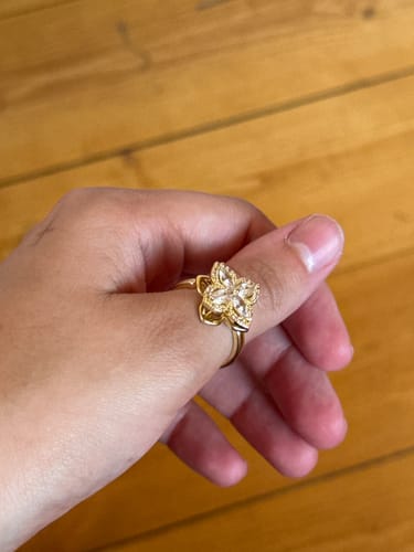 Reviewer's gold Calmy fidget ring with a floral shape on their finger.