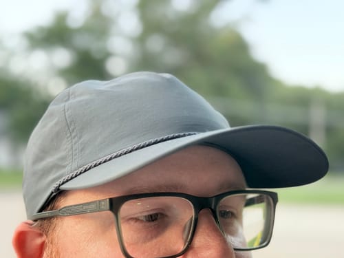 Customer's grey Big Lightweight Nylon Hat on head, featuring a curved bill and glasses