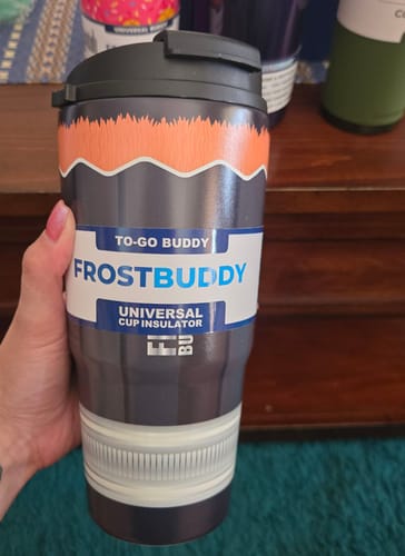 Customer's hand holding a dark colored Mystery To-Go Buddy cup with an orange and white graphic pattern.