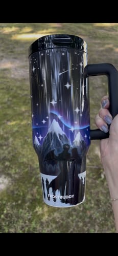 Customer's Thicc Buddy 40oz cup with a mountain and star night theme, held in a hand outdoors.