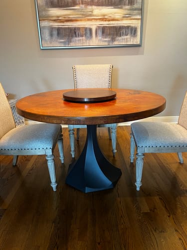 Customer's black Lithe Table Base 311 supporting a round, copper-toned tabletop in a dining room.