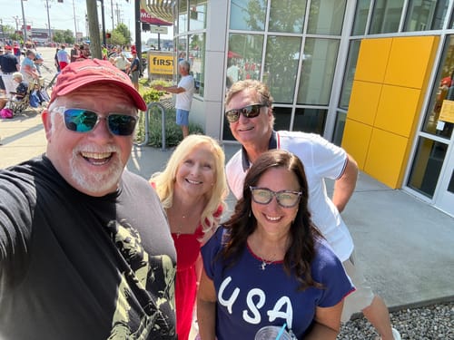 A smiling reviewer wearing the Lincoln Guitar T-Shirt in a group selfie outdoors.
