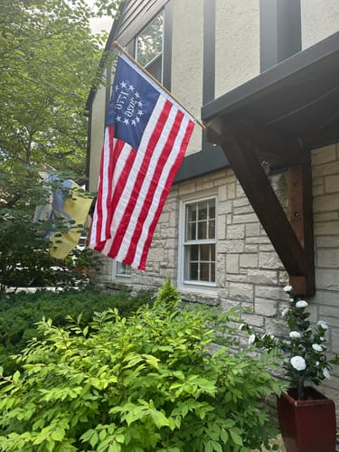 Reviewer's 1776 to 2026 Betsy Ross Flag flying from a pole on the side of a house.