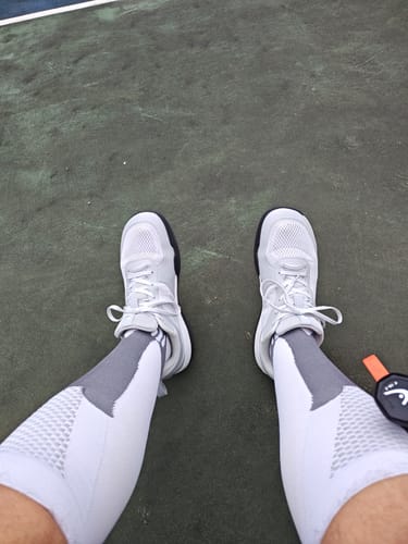 Reviewer wearing white CUURT Muuv court shoes with a wide toe box on a green court.