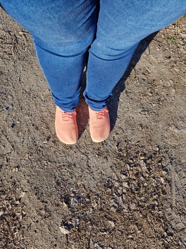 Reviewer's peach-colored Vaistoa Iloa paljasjalkatennarit worn with blue jeans, standing on a dirt trail.