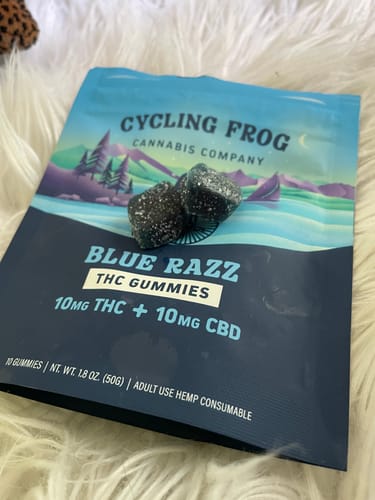 Customer's Blue Razz Gummies pouch with two dark, sugar-coated gummies resting on top.