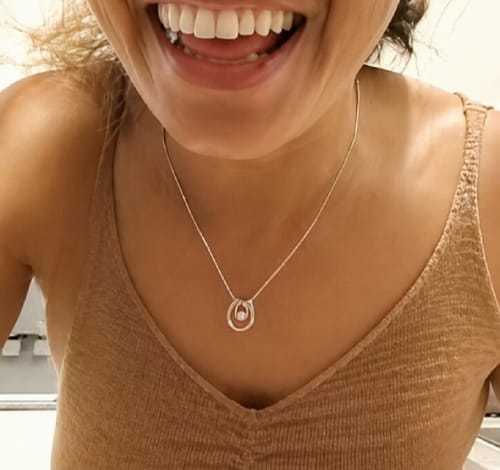 Reviewer smiling while wearing the beautiful gift set necklace with a double-ring pendant.
