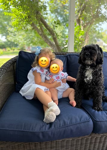 Customer's two young children wearing matching Flag Smocked White Pique Bubbles while sitting on a patio couch.