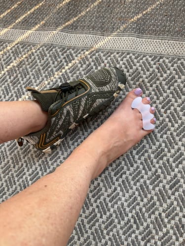 Customer showing one foot in an Active II Pro Barefoot Shoe and their other bare foot with a toe separator.
