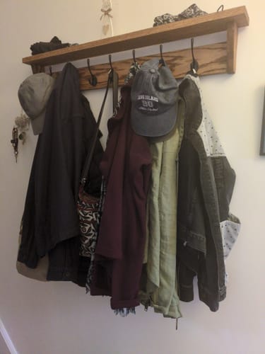 Reviewer's beautiful walnut coat rack with shelf, mounted on a hallway wall and loaded with coats and hats.